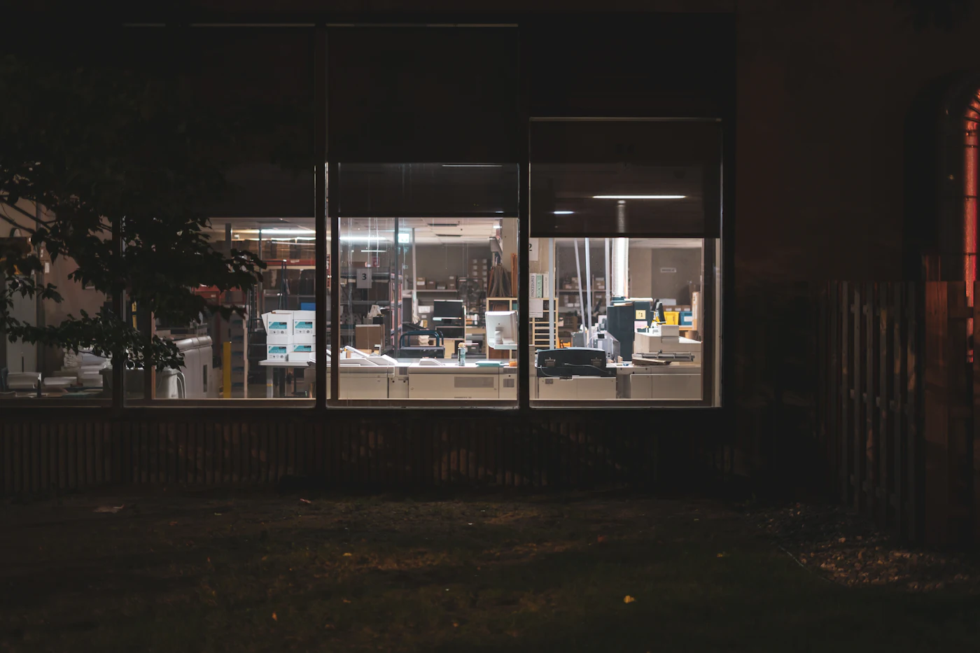 Un'officina illuminata vista da fuori, di notte, a saracinesche chiuse